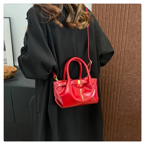 Detail of red pleated bucket bag featuring gold metal hardware and sleek leather texture