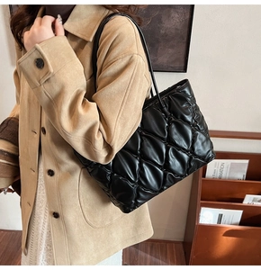 Close-up of a black quilted tote bag with glossy texture and elegant shoulder straps