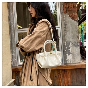 Detail of cream pleated handbag with gold hardware and stylish dumpling shape design