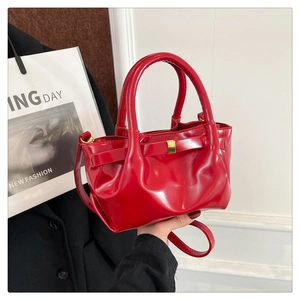 Detailed close-up of bright red pleated bucket bag with gold metal buckle and dual handles