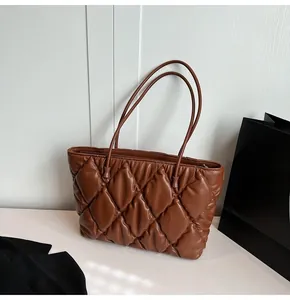 Close-up of brown quilted tote bag with diamond lattice pattern and leather straps