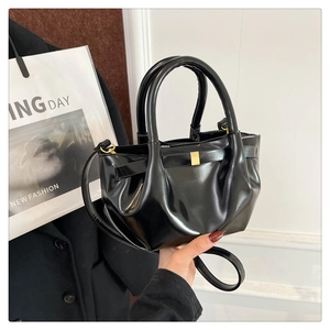 Detail of black glossy PU leather handbag featuring pleated texture and golden square buckle