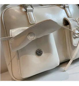 Detail of a creamy white leather bag with glossy finish and silver magnetic buckle closure