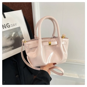 Detail of light pink patent leather handbag with gold buckle and pleated texture design