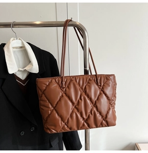 Detail of a brown quilted tote bag with diamond pattern on a professional office outfit