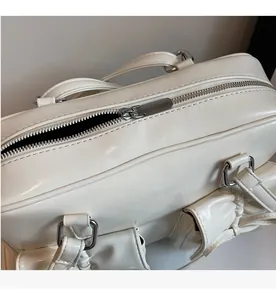 Detail of smooth silver metal zipper closure and handle hook on white shoulder bag