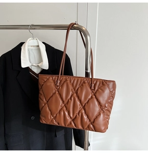 Detail of dark brown quilted leather tote bag with large capacity and shoulder straps