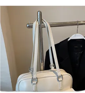 Detail of white cream PU leather tote bag with slender straps and metallic buckles