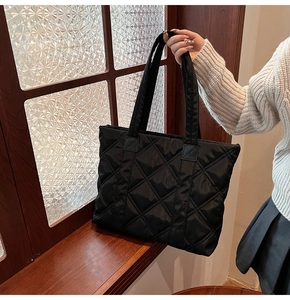 Detail of black quilted puffer tote bag in glossy nylon with padded diamond pattern texture