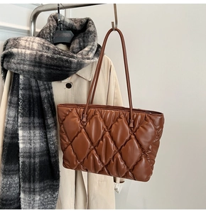 Detail of caramel brown quilted tote bag showing plush diamond texture and shoulder strap