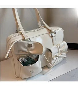Close-up of cream white shoulder bag with bow-knot pockets and metallic snap buttons