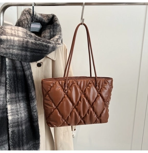 Close-up of brown quilted leather tote bag with diamond pattern on a display stand