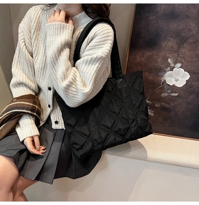 Dettaglio della borsa tote in nylon nero trapuntato con motivo a rombi e tracolla