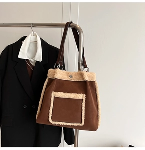 Detail of faux suede tote bag with fleece trim hanging on a rack with a blazer