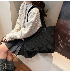 Close-up of black quilted nylon tote bag with rhombus pattern on shoulder