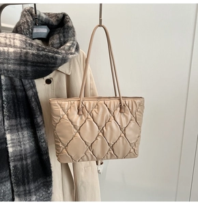 Close-up of beige quilted tote bag showing fluffy rhombic texture and shoulder strap