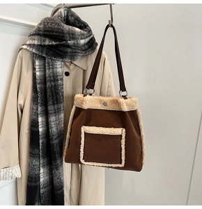 Close-up of brown suede bucket bag featuring beige fleece trim and vintage shoulder strap