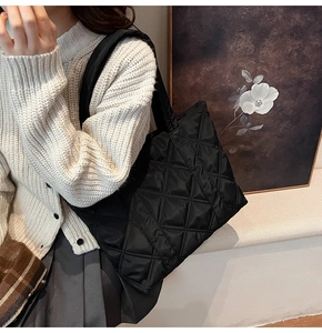 Close-up of black quilted nylon tote bag with rhombus embroidery and soft texture