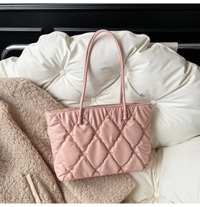 Close-up of pink quilted tote bag with soft leather texture on a white leather sofa