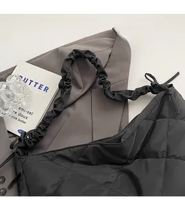 Detail of black quilted nylon bag with cloud-shaped pleated strap and diamond pattern