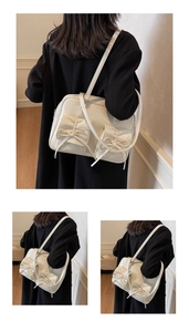 Detail view of cream shoulder bag with stylish bow knots and functional front flap pockets