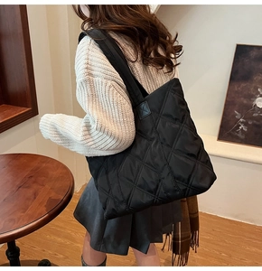 Detail of black quilted nylon tote bag with diamond stitching worn by model