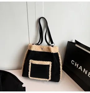 Detail of black suede tote bag with white faux shearling trim and leather handles