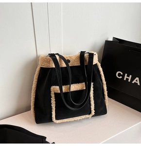 Detail of a large black tote bag featuring soft beige faux fur trim and dual shoulder straps