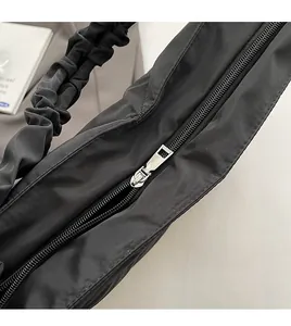 Detail of smooth metal zipper and textured black nylon fabric on the quilted tote bag