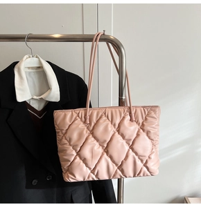 Detailed view of light pink quilted tote bag with diamond stitching on a minimalist hanger