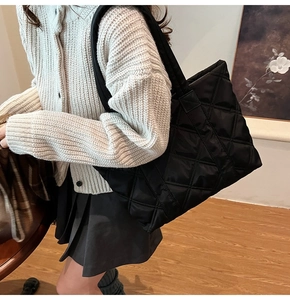 Close-up of black quilted nylon tote bag with elegant rhombus embroidery and metal details