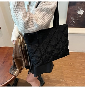 Close-up of black quilted tote bag showing detailed diamond stitching and nylon texture