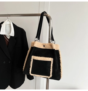 Detail of large black suede tote bag with plush white trim hanging on a metal rack