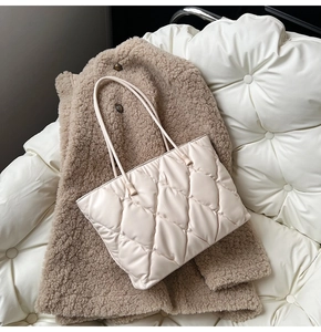 Detail of cream white quilted tote bag with glossy finish and dual shoulder straps