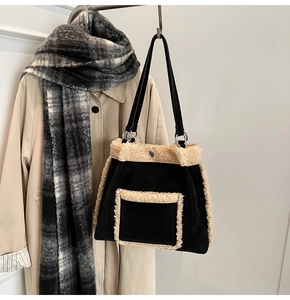 Detail of faux shearling trim on black tote bag with silver hardware and shoulder strap