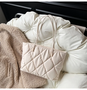 Close-up of cream quilted tote bag showing plush texture and fine stitching detail