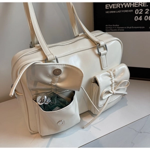 Detail of cream white shoulder bag with decorative bows and dual magnetic flap pockets
