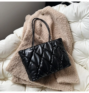 Detail of black quilted leather tote bag featuring a diamond pattern on textured fabric