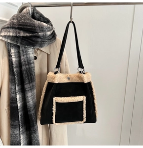 Close-up of black suede tote bag with beige shearling trim on a coat hanger