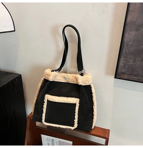Detail of suede tote bag with faux fur trim and leather strap on a vintage wooden shelf