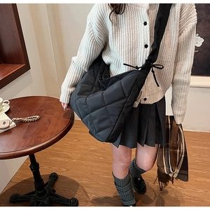 Detail of black quilted nylon tote bag featuring oversized bow strap on the shoulder