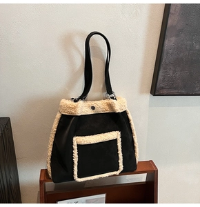 Detailed close-up of fluffy faux shearling trim on a chic black suede tote handbag