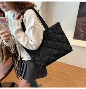 Detailed view of the black quilted nylon fabric texture and stitching on the tote bag