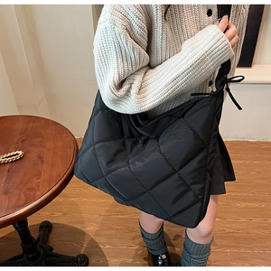 Close-up of black quilted nylon bag with bow detail and soft padded texture