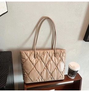 Close-up of beige quilted tote bag showing cloud-like texture and leather handle