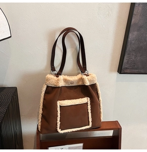 Detail of suede tote bag with cream faux fur trim on a rustic wooden shelf