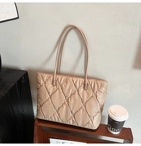 Detail of beige quilted tote bag showing high-gloss diamond texture and shoulder straps