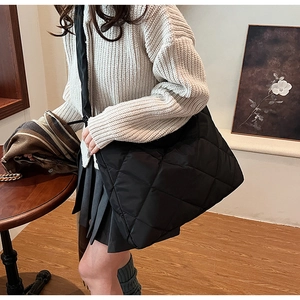 Detail of black quilted nylon bag showing large capacity and rhombic stitching texture