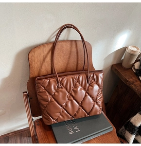 Close-up of dark brown quilted tote bag with soft PU leather texture on a wooden chair