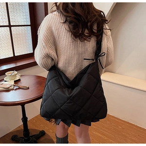 Detail of black quilted nylon tote bag with decorative bow and textured bubble fabric